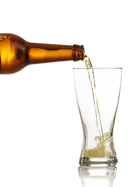 Пивная бутылка, наливающая золотое пиво в стакан, белый фон, крупным планом обрезанный портрет - Фото, изображение