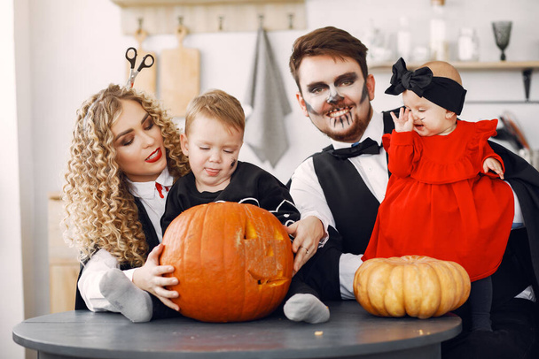 Family in costumes getting ready for halloween at home - 写真・画像