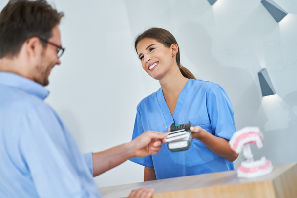 Пациент оплачивает визит стоматолога в клинику - Фото, изображение