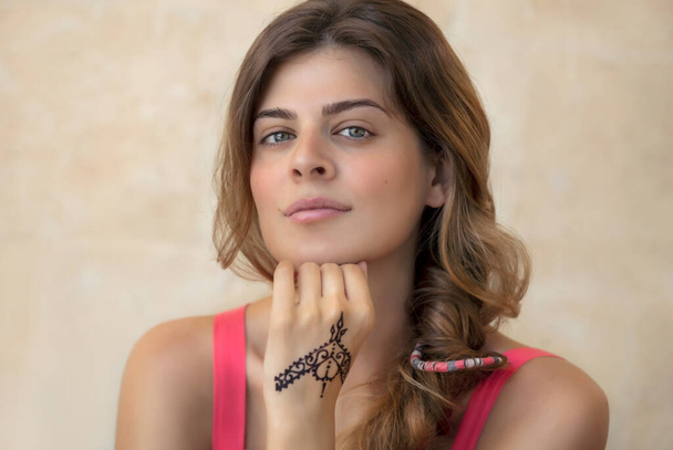 Portrait of an Attractive Woman Isolated on Beige Background with Beautiful Henna Drawing on the Hand. Stylish Body Art. Authentic Beauty of Young Female. - Φωτογραφία, εικόνα