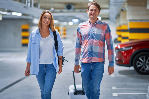 Paar toeristen in ondergrondse luchthaven parkeerplaats - Foto, afbeelding