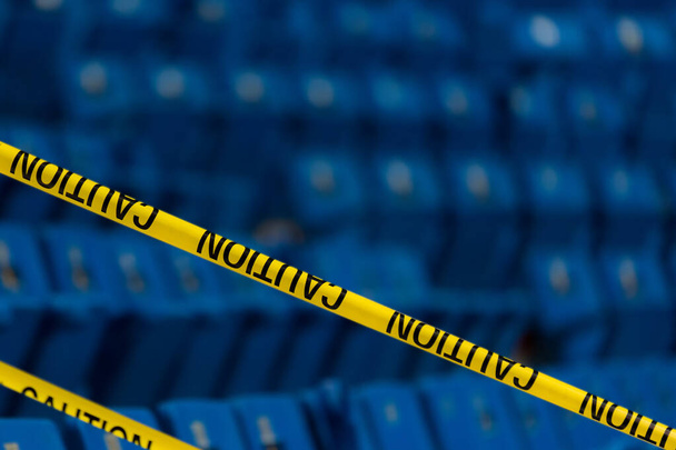 Sárga figyelmeztető szalag egy stadionban. Kék ülések vannak a háttérben. A fenti szöveg helye. - Fotó, kép