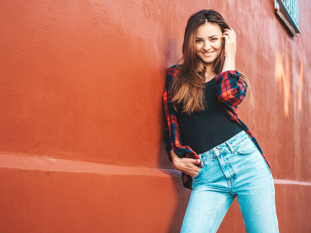 Portrait of beautiful smiling model. Female dressed in summer hipster checkered shirt and jeans. She posing near wall in the street. Funny and positive woman having fun outdoors - Foto, imagen