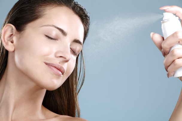 Beautiful woman applying spray  water treatment on face - Фото, изображение
