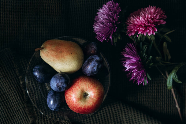 still life in a dark key fruits and flowers - Photo, Image