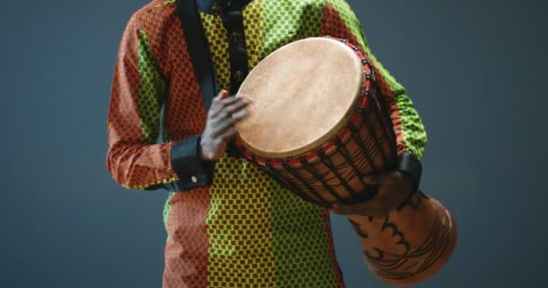 Primo piano di mani maschili afroamericane che picchiettano e tamburellano sul bongo. Musicista in abiti tradizionali. Il batterista della tribù africana che suona la batteria. Performance musicale. - Filmati, video