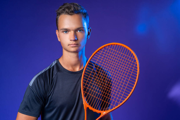 Caucasian young man tennis player posing with tennis racket against purple background - Foto, Imagem