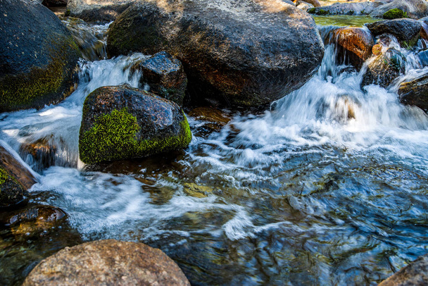  wirbelndes Weißwasser, das um große Felsen im Gebirgsstrom Kaliforniens fließt - Foto, Bild