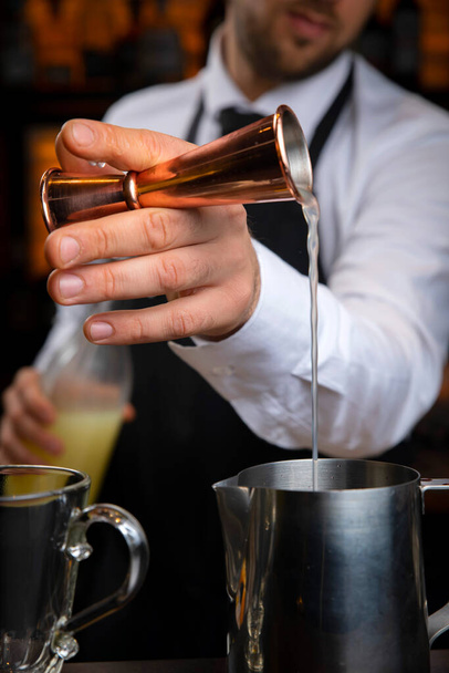 A young smiling bartender in a black apron prepares mulled wine - Fotoğraf, Görsel