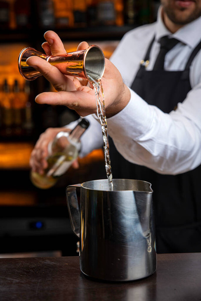 A young smiling bartender in a black apron prepares mulled wine - Foto, Imagem