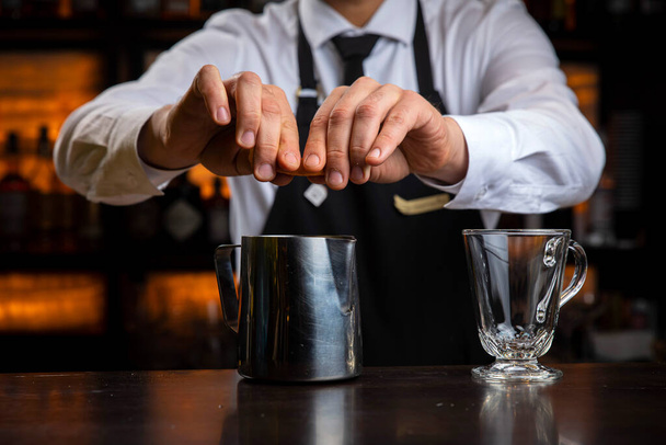 A young smiling bartender in a black apron prepares mulled wine - Photo, Image