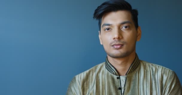 Portrait shot of handsome young Hindu cheerful man in traditional clothes smiling to camera. Close up of attractive happy guy laughing joyfully. Indoor. - Footage, Video
