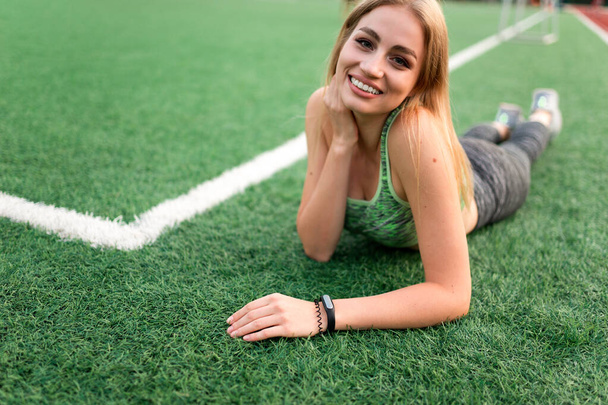 Fitness girl lying on the grass of a soccer field - Фото, зображення