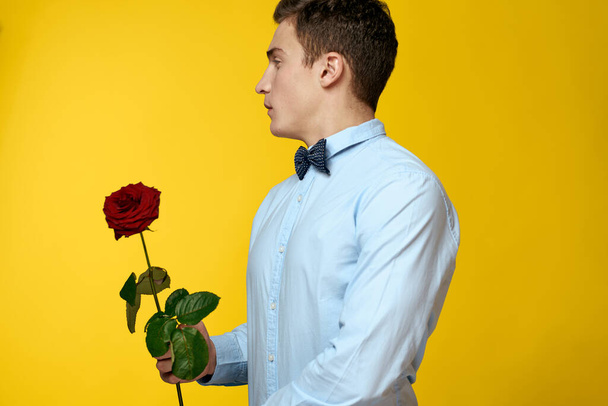 Gentleman in shirt and bow tie around his neck yellow background red rose - Photo, Image