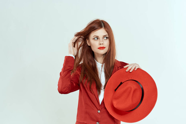 Elegant woman in red jacket hat holding long hair cropped light background - Photo, Image