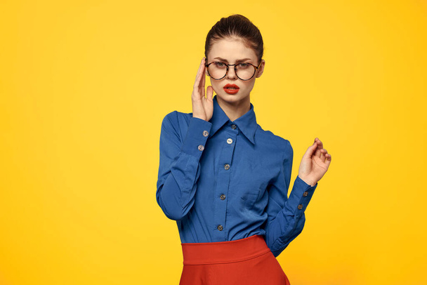 Nő kék ing és piros szoknya szemüveg az arcon magabiztos megjelenés portré sárga háttér kivágott kilátás - Fotó, kép