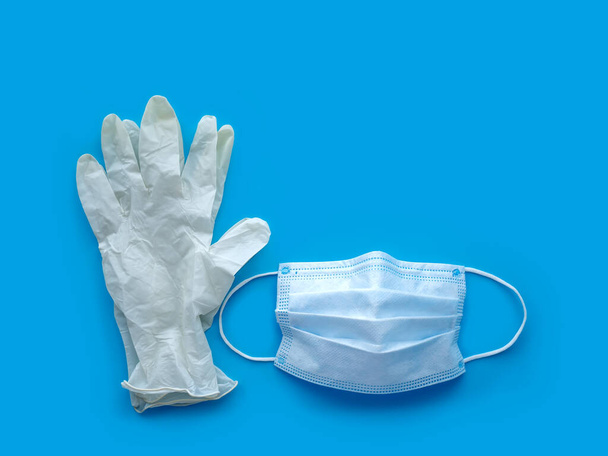 Ochrona antywirusowa. Gumowe rękawiczki i maska medyczna na niebieskim tle. Ochrona przed grypą. Ncov-19 pandemia koronawirusa. - Zdjęcie, obraz