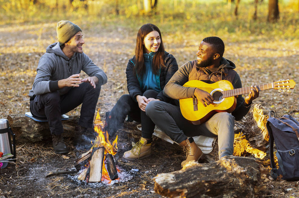 Grupo de amigos acampando y cantando en bosques de otoño - Foto, Imagen
