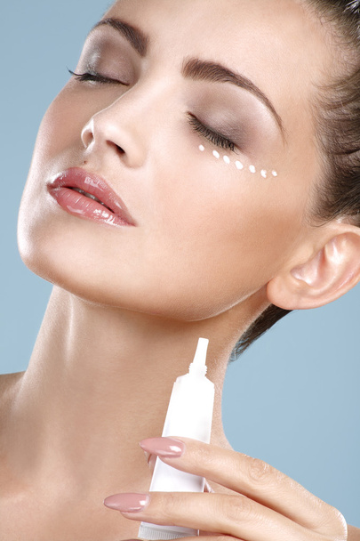 Beautiful woman applying cream treatment on her perfect face - Photo, image