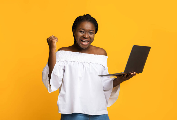 Ah oui ? Lady afro-américaine excitée célébrant le succès avec ordinateur portable, secouer le poing - Photo, image