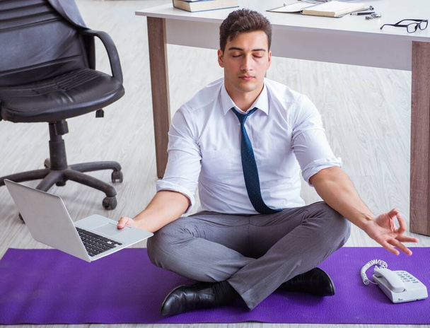 Man meditating in the office to cope with stress - 写真・画像