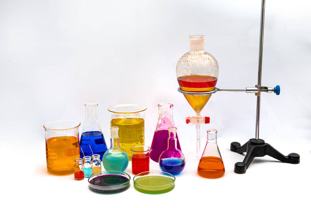 Chemisch laboratoriumglaswerk met diverse gekleurde vloeistoffen op tafel. Laboratoriumonderzoek - Wetenschappelijk glaswerk voor chemische achtergrond. - Foto, afbeelding