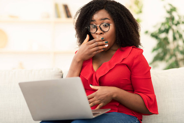 Kanepede dizüstü bilgisayar kullanan siyahi bir kadın. - Fotoğraf, Görsel
