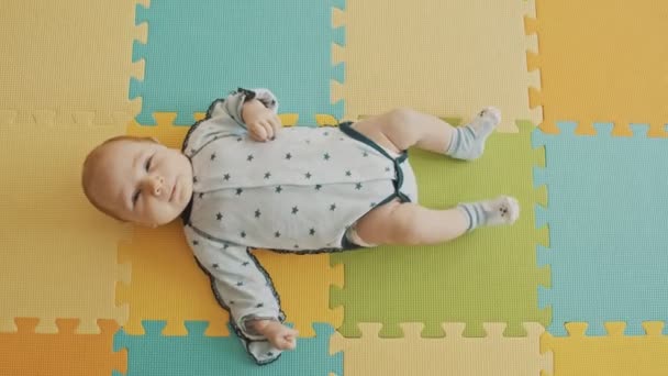 Pequeño niño acostado boca arriba en la alfombra de pastel - Imágenes, Vídeo