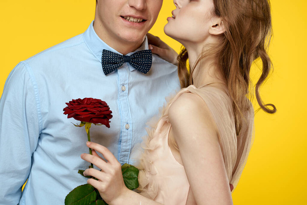 Enamored man and woman with red rose on yellow background cropped view close-up romance - Fotografie, Obrázek