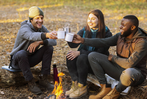Cheerful hikers toasting for nice camping in sunset lights - Фото, изображение