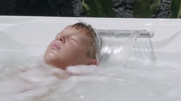 Chłopiec relaksujący się w jacuzzi - Materiał filmowy, wideo