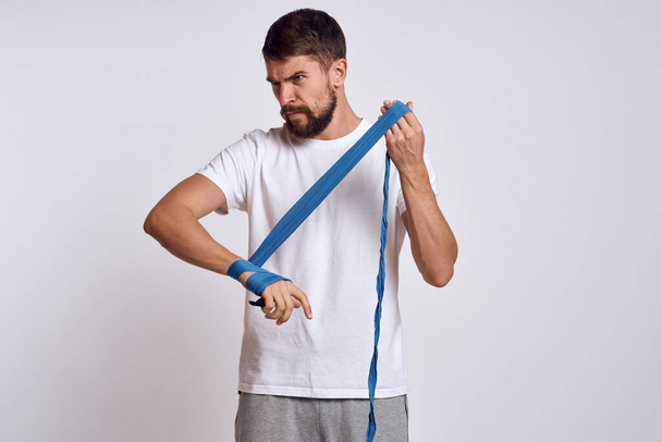 スポーツマンで白いTシャツ青いボクシングの包帯で彼の腕のトレーニング演習 - 写真・画像