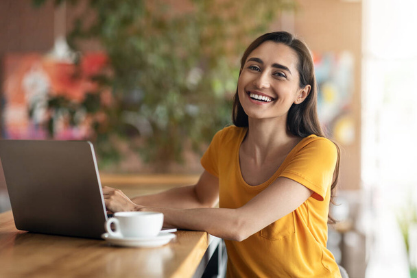 Cheerful arab lady sitting in front of laptop at cafe - Photo, Image