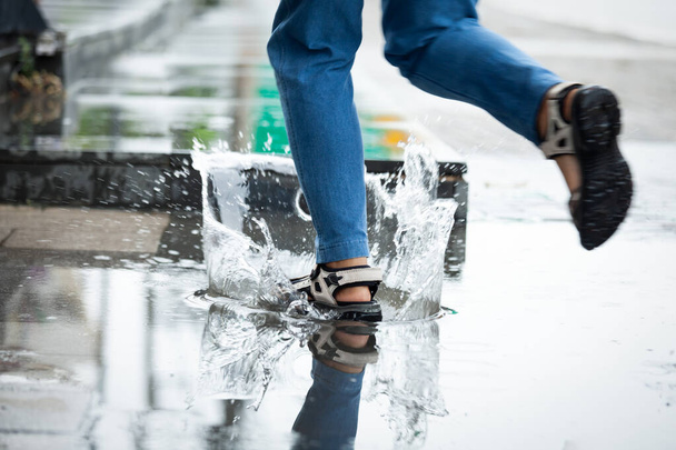 Yağmurlu bir günde su birikintilerinde koşan bir kadının ayakları - Fotoğraf, Görsel