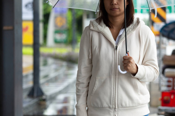 Asian woman holding umbrella while waiting taxi and standing on the city sidewalk street in the rainy day. - Foto, Bild