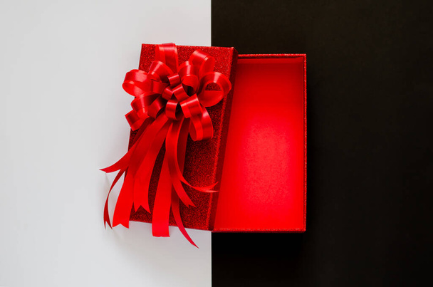 Boîte de Noël rouge avec ruban papillon rouge sur fond noir et blanc. Concept Black Friday. - Photo, image