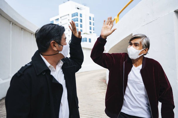 Retrato de moda de dos ancianos de edad avanzada que usan máscara haciendo cinco altos. - Foto, imagen