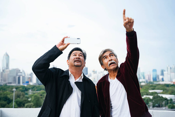 Portrét starých starších podnikatelů držících smartphone kontrolu nemovitosti budovy ve městě. - Fotografie, Obrázek
