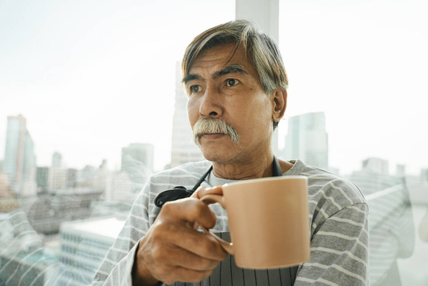 Gros plan de vieil homme âgé asiatique tenir une tasse de café. - Photo, image