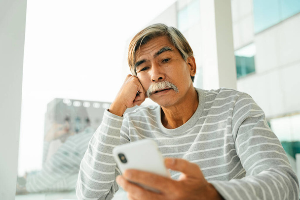 Idős idős férfi használ okostelefon szörf az interneten. - Fotó, kép