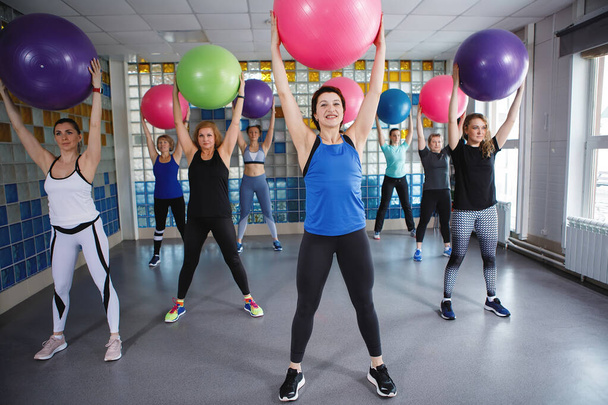 Les femmes tiennent une balle de fitness dans la salle de gym. Entraîneur adulte au premier plan. Objet sélectionné. - Photo, image