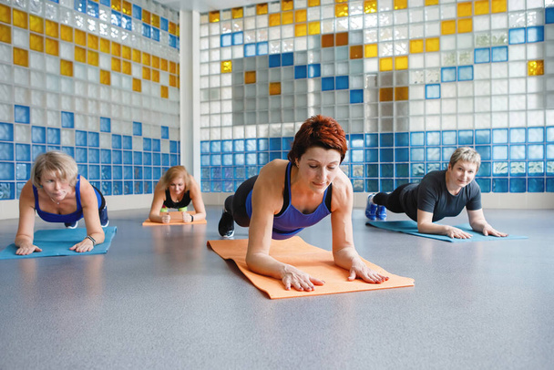 Women do elbows plank on a yoga or fitness mat in the gym. - Photo, Image