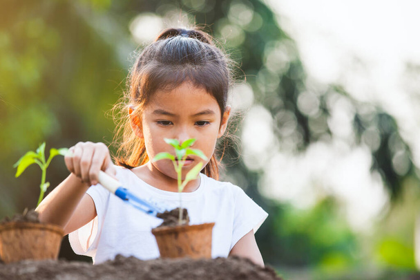 Mignon asiatique enfant fille plantation jeune arbre dans recycler des pots de fibres dans le jardin avec plaisir - Photo, image
