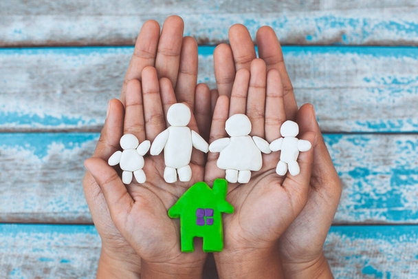 Пластиковые когти счастливой семьи и дома на руках ребенка и родителей. Счастливая семья и теплый дом. - Фото, изображение