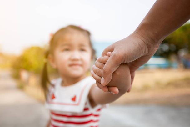 Eltern und asiatische Kindermädchen halten Hand in Hand mit Liebe und Fürsorge - Foto, Bild
