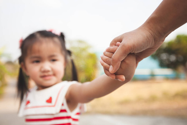 Батько і азіатська дівчинка тримає руку разом з любов'ю і турботою
 - Фото, зображення