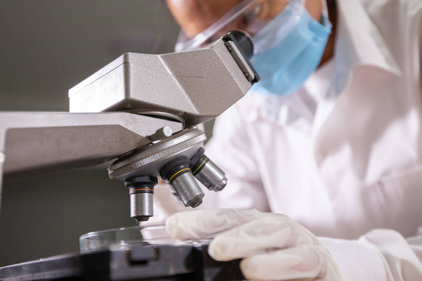 Азиатский ученый рассматривает микроскоп для исследования и анализа химических тестов в лаборатории - Фото, изображение