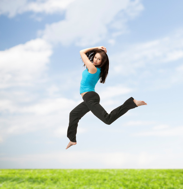 スポーティな女性スポーツ ウエアでジャンプ - 写真・画像