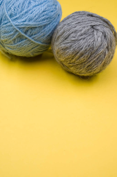 A vertical shot of two balls of yarn on a yellow surface - Φωτογραφία, εικόνα