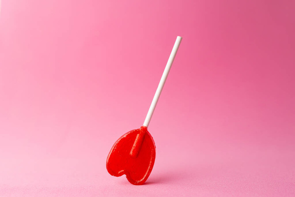 A closeup shot of a single heart-shaped lollipop on a pink background - Valokuva, kuva